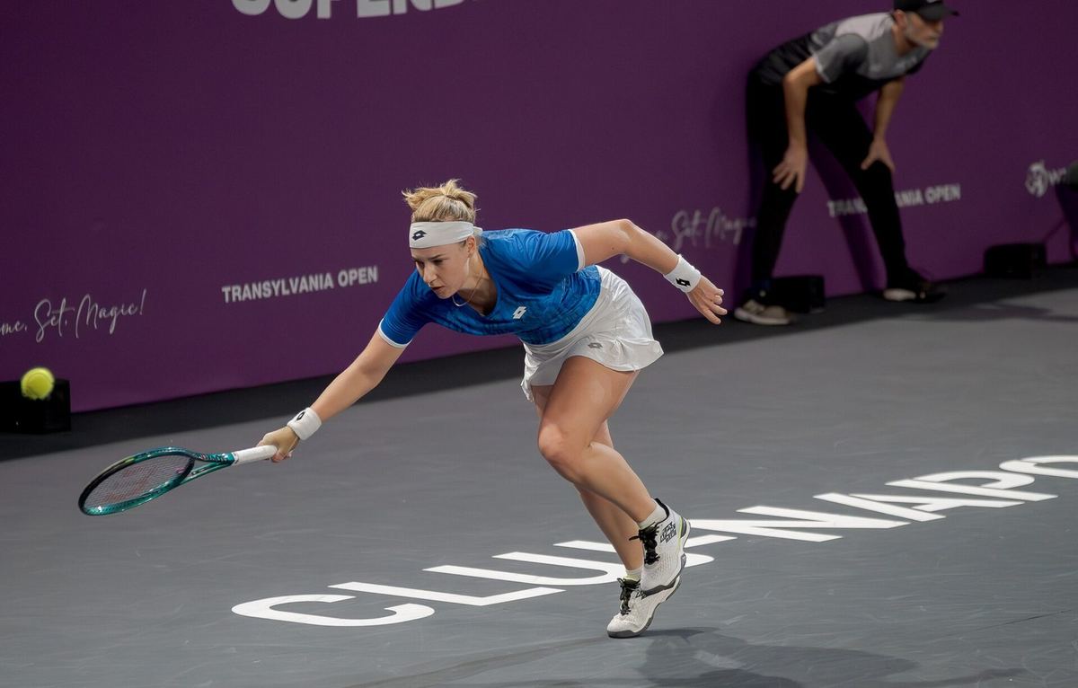 Anna Blinkova stretching for a forehand on an indoor hard court in Cluj-Napoca