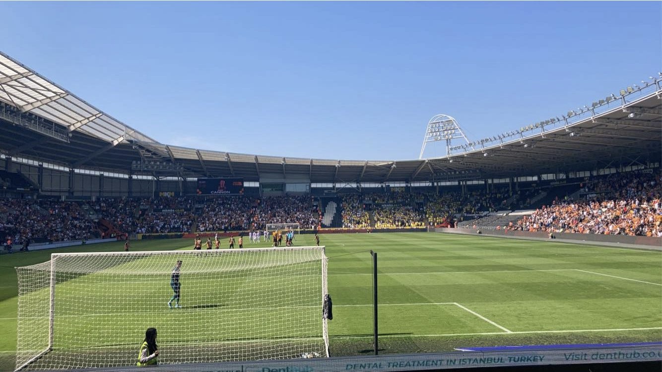 Inside the MKM Stadium in Hull on a match day, the pitch and a goal in the foreground and a packed crowd across the stands